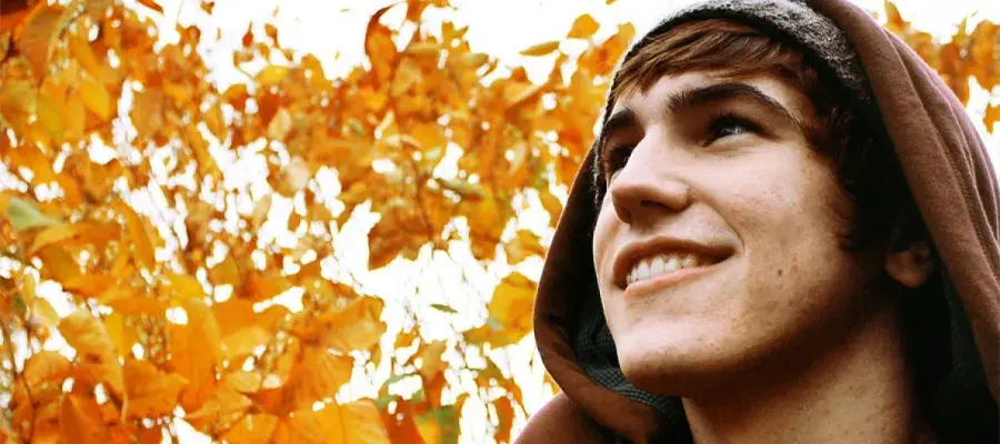 Man looking up with leaves behind him