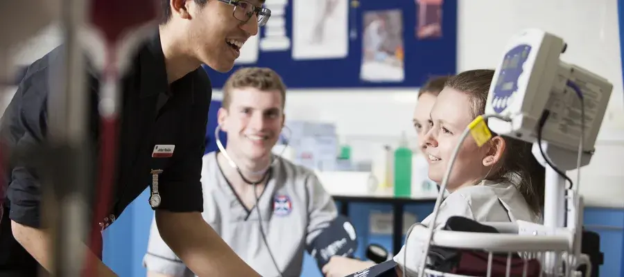 A group of nursing students are being shown how to use medical equipment in one of their clinical elective classes