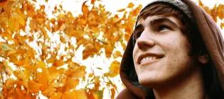 Man looking up with leaves behind him