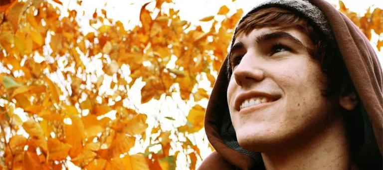 Man looking up with leaves behind him