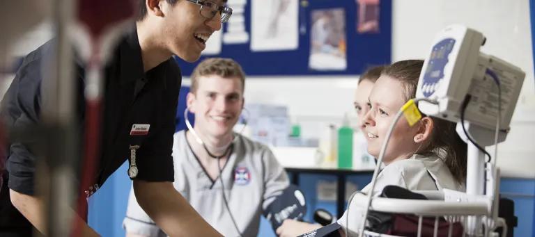A group of nursing students are being shown how to use medical equipment in one of their clinical elective classes
