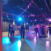 A group of students are paired up and dancing with each other at a ceilidh