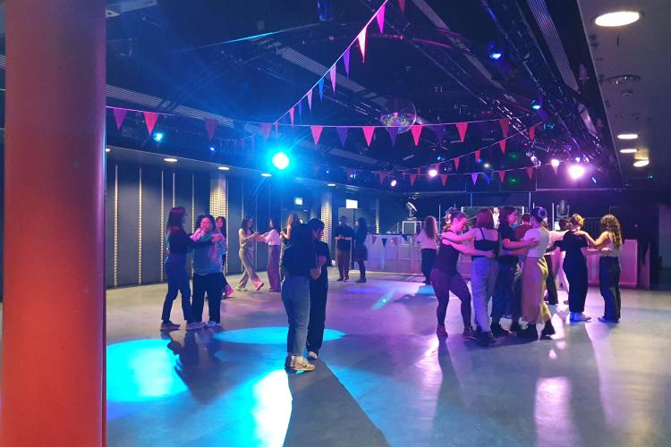 A group of students are paired up and dancing with each other at a ceilidh