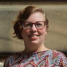 Louise is smiling warmly at the camera on a sunny day