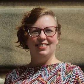 Louise is smiling warmly at the camera on a sunny day