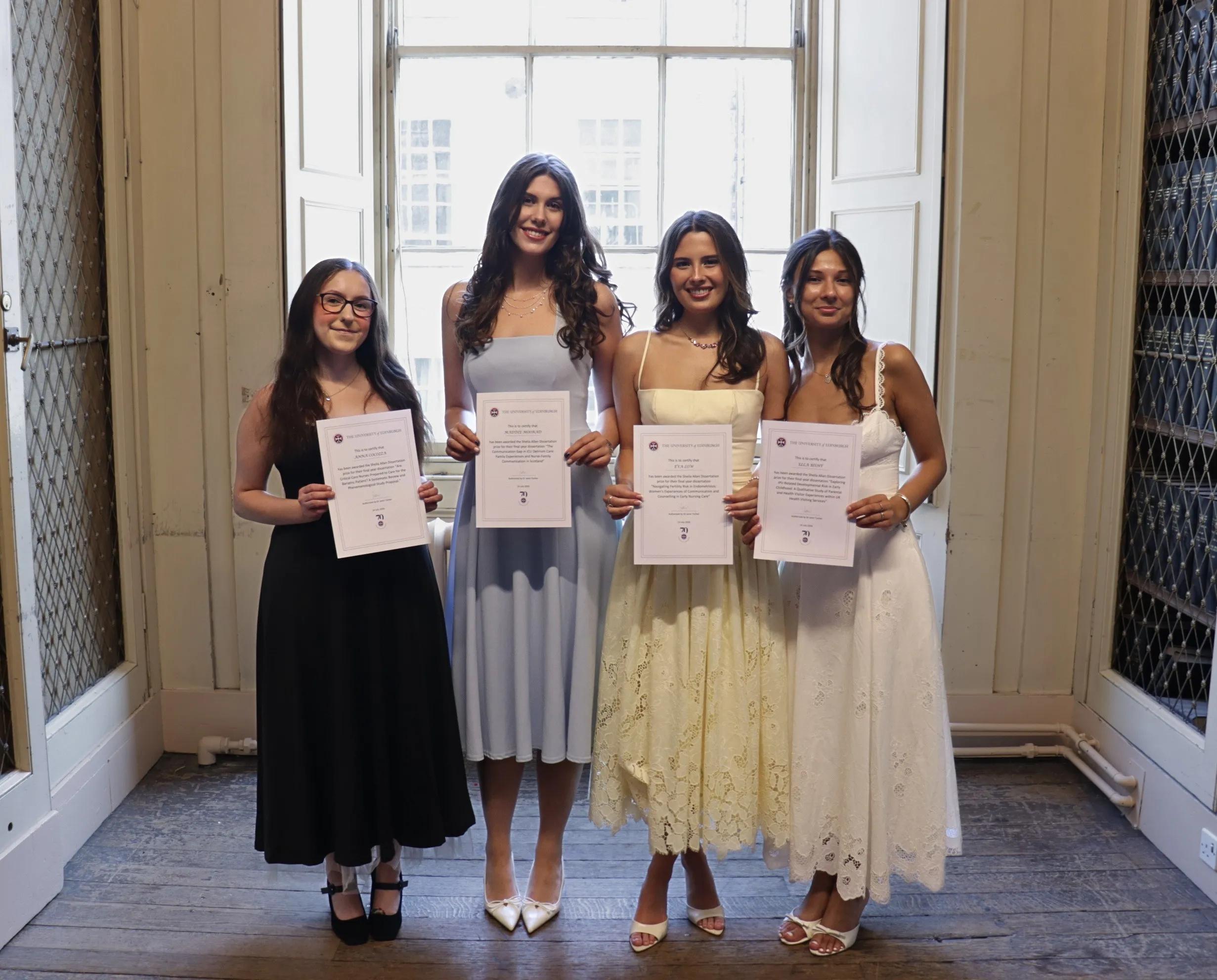 Four proud graduates pose with their award certificates