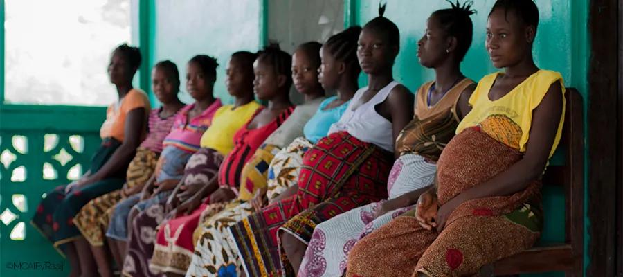 Pregnant women sitting in a row outside a Liberian 'waiting home