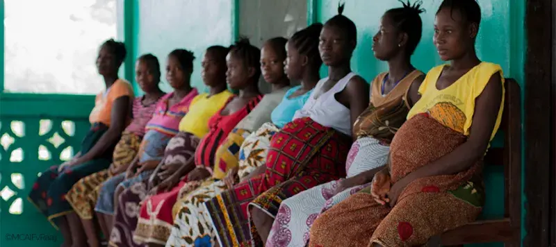 Pregnant women sitting in a row outside a Liberian 'waiting home